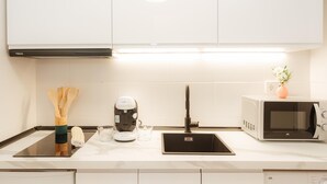 Keittiössä on musta induktioliesi, ruostumattomasta teräksestä valmistettu pesuallas, valkoinen mikroaaltouuni ja kahvinkeitin.