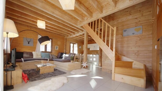 Un interior de madera con una escalera, un sofá, una mesa de centro y una lámpara.