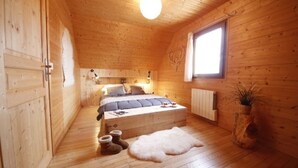 Dormitorio de cabaña de madera con cama, mesita de noche y ventana.