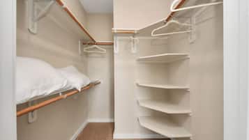 Ein kleiner, schmaler Raum mit einem Etagenbett, einem Holzbodenregal und einem weißen Kleiderschrank mit Kleiderstange.