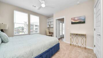 Un dormitorio con cama, ventilador de techo, televisión y vistas al exterior.