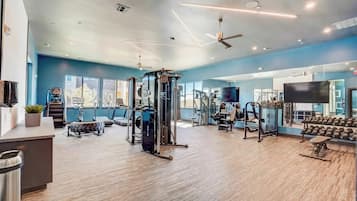 Un gimnasio con equipos de ejercicio variados, un espejo y una televisión.