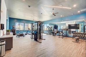 Une salle de sport équipée de divers appareils d’exercice, d’un miroir et d’un téléviseur.