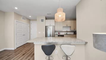 Una cocina moderna con encimeras de granito, electrodomésticos de acero inoxidable y una lámpara colgante.