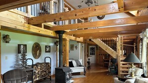 A spacious living area with a high ceiling, wooden beams, a fireplace, and a staircase leading to an upper level. - Destination Meadowland, Ride N Relax Grey/Bruce County...motorcycle friendly (Wiarton)