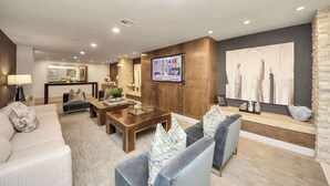 Una sala de estar moderna con un sofá, sillones, una mesa de centro y un televisor montado en la pared.