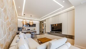 Een moderne woonkamer met een bank, een salontafel en een televisie aan de muur.