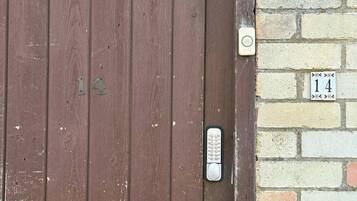 A wooden door with the number 14, a keypad lock, and a brick wall with a number 14 sign.
