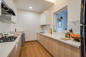 A modern kitchen with a gas stove, wooden cabinets, a window, and a fruit bowl.