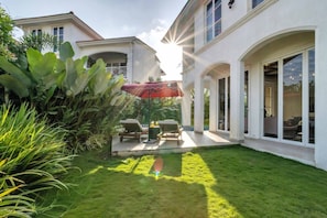A house with a patio, a red umbrella, and a well-maintained lawn.