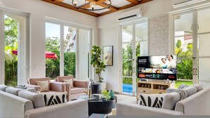 A modern living room with a TV, sofas, and a large window. - Villa Sai Shukhrana 3bhk w Private Pool in Moira (Moira)