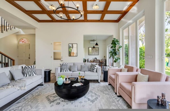 A spacious living room with a high ceiling, a black coffee table, and a staircase leading to another level.