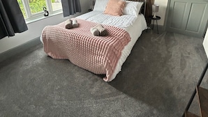 Quarto com cama, janela, porta e vista para o verde lá fora.