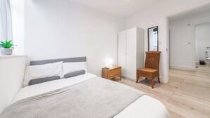 Ein Schlafzimmer mit Bett, Nachttisch, Sessel, Kleiderschrank und Spiegel.