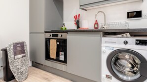 Une cuisine moderne équipée d’un four encastré, d’un lave-linge et d’une poubelle.