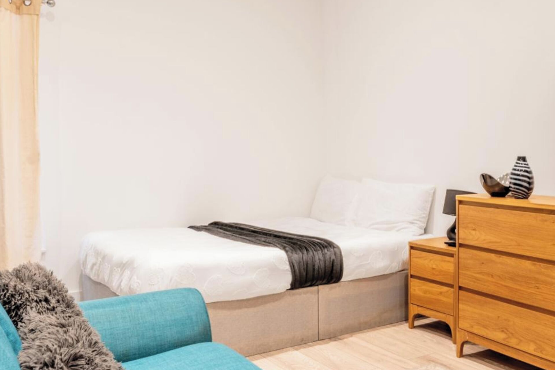 Un dormitorio con cama, cómoda y una silla azul.