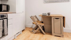 Una cocina compacta con microondas, horno y una silla plegable.