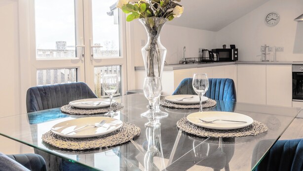 Une table à manger dressée avec des assiettes, des couverts et un vase rempli de fleurs.