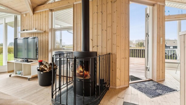 Ein Holzinnenraum mit Kamin, Fernseher und Blick ins Freie.