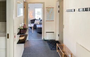 A hallway with a black mat, a wooden rack, a map, and a sofa in the background. - 2 bedroom awesome apartment in Rudkøbing (Rudkøbing)