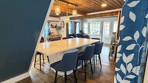 Et interiør med træloft, et køkkenområde med bar og et spiseområde med stole.