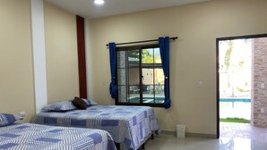 A hotel room with two beds, a window with curtains, a tiled floor, and a view of the outside.