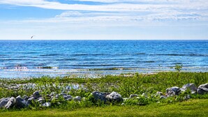 Paisaje costero con cielo despejado, mar tranquilo y costa rocosa con vegetación.