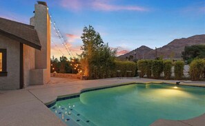 Una piscina con una vista despejada del cielo y montañas al fondo.