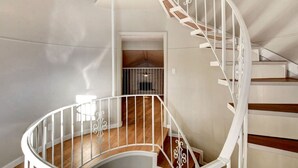 Una scala a chiocciola con ringhiere bianche e gradini in legno, che conduce a un piano superiore.