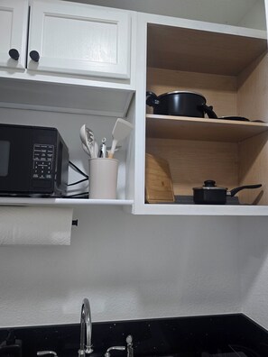 A kitchen with white cabinets, a microwave, a sink, and a shelf with kitchen utensils. - Luxurious suits with independent entrance 15 mnts from the Strip (Las Vegas)