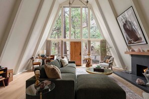 A cozy living room with a large window, a fireplace, and a comfortable seating area.