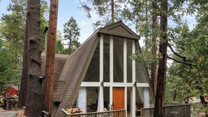 Eine Hütte mit geneigtem Dach, großen Fenstern und einer Holzterrasse.