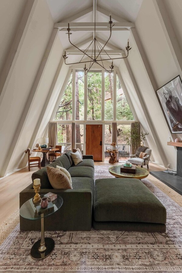 A spacious loft with a large window, a modern chandelier, and a cozy seating area.