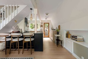 A modern kitchen with a central island, bar stools, and a staircase.