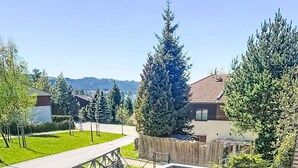 Une terrasse extérieure aménagée avec des meubles en osier, une cl ôture en bois et une vue sur un quartier résidentiel.