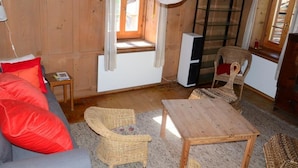 A wooden interior with a sofa, two wicker chairs, a small table, a TV, and a window with curtains. - Obergasse Ferienhaus, Dusche oder Bad, WC Ferienhaus by Interhome (Wiesen)