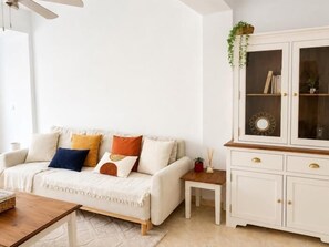 Un salon comprenant un canapé, une petite table, un meuble et un ventilateur de plafond.