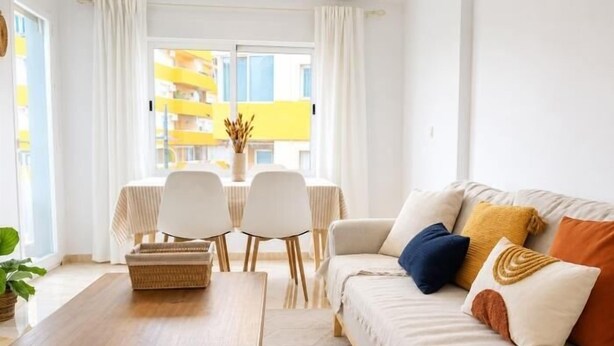 Una sala de estar con sofá, una mesa de centro y un comedor con sillas y una mesa.