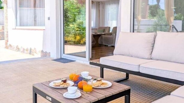Un espace extérieur moderne, aménagé avec un canapé et une table où sont disposés des éléments pour le petit-déjeuner.
