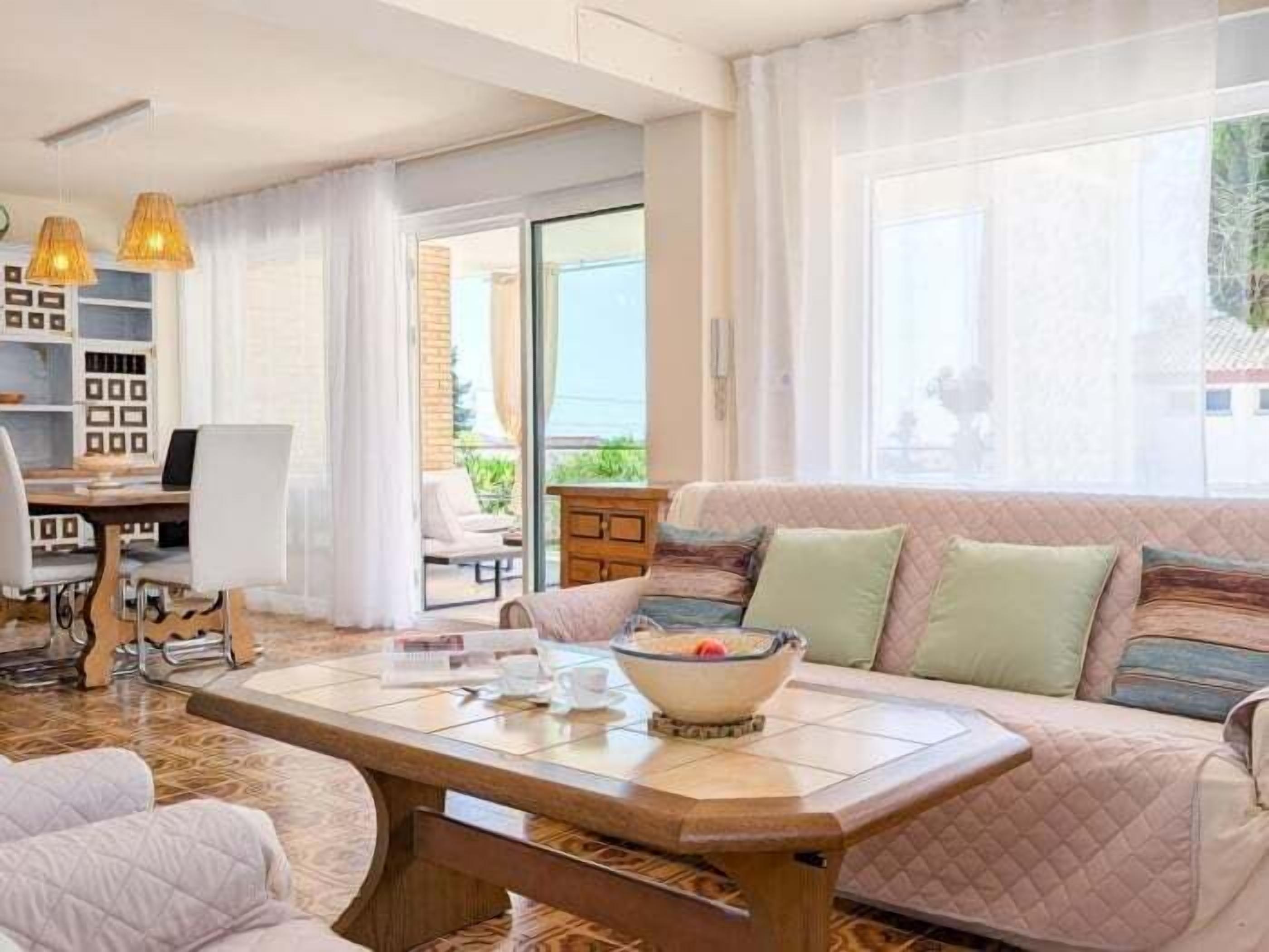 Een moderne woonkamer met een bank, een salontafel, een eettafel en uitzicht op het groen.