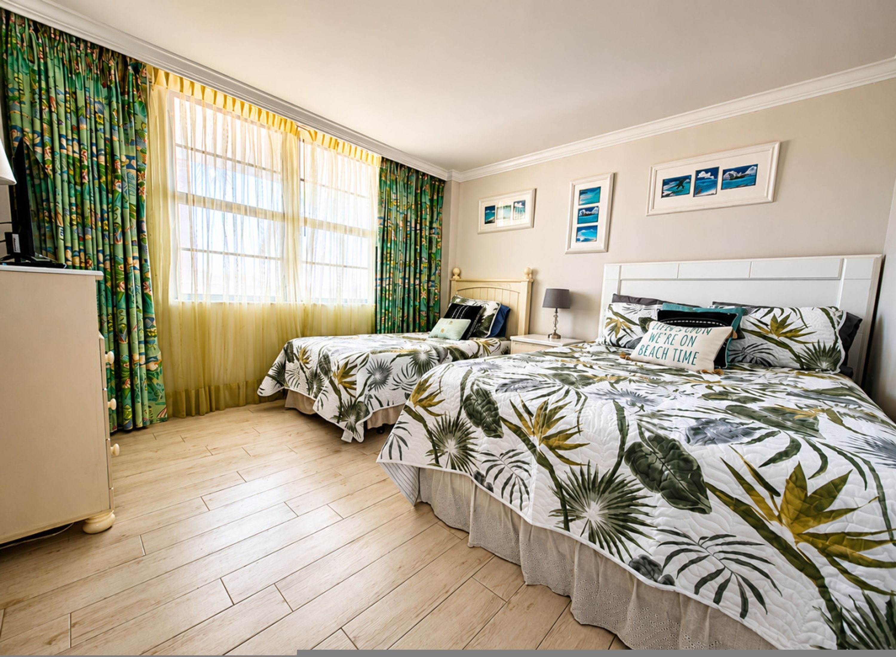Ett hotellrum med två sängar, en garderob, ett skrivbord och ett fönster med gardiner.