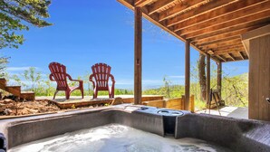 A hot tub with two Adirondack chairs, a wooden deck, and a view of the mountains. - Blue Mt. Ridge Cabin with Long Range Views, Hot Tub & Fire Pit Fun near Parkway! (Watauga County)