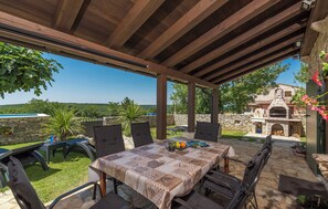 Un patio exterior con una mesa y sillas, un muro de piedra y una vista de un edificio de piedra al fondo.