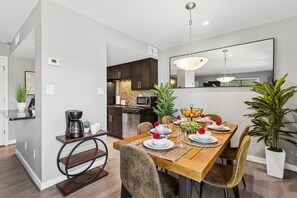 Ein moderner Essbereich mit Holztisch, Stühlen und einer Küche im Hintergrund.