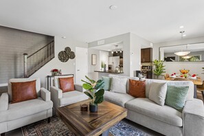 Ein modernes Wohnzimmer mit Treppe, Essbereich und Küche.