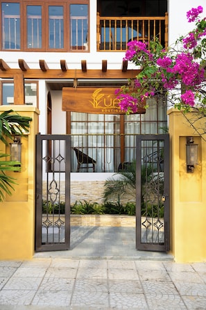 A boutique hotel entrance with a wooden pergola, a sign above the door, and a gate. - Lua Boutique Hotel & Spa - An Bang Beach (Da Nang)