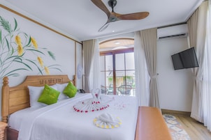 Habitación de hotel con una cama, ventilador de techo, televisión y vistas al exterior.