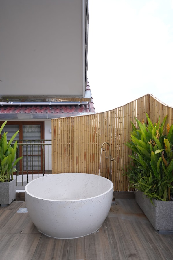 A large outdoor hot tub on a wooden deck with a bamboo fence and potted plants. - Lua Boutique Hotel & Spa - An Bang Beach (Da Nang)