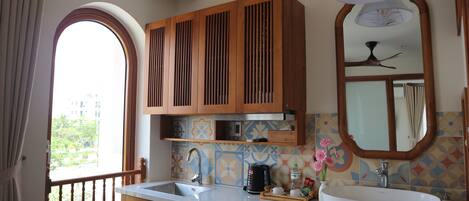 A kitchen with wooden cabinets, a white sink, and a window with a view of greenery.