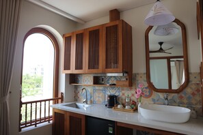 Una cocina con armarios de madera, un lavamanos blanco y una ventana con vistas a la vegetación.